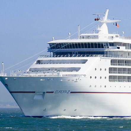 Ein großes Kreuzfahrtschiff fährt über das ruhige Wasser.