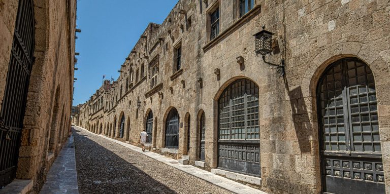 Blick auf eine alte, gepflasterte Straße mit historischen Gebäuden in der Stadt Rhodos.