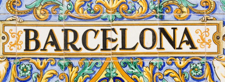 Straßenschild mit dem Text "BARCELONA" in kunstvollem, buntem Stil.