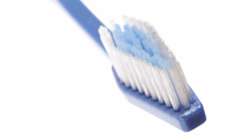 Blaue Zahnbürste mit weißen Borsten, leicht schräg gehalten.