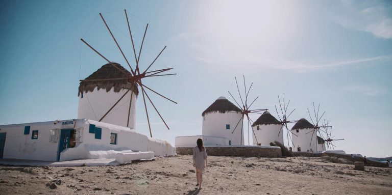 Fünf traditionelle Windmühlen vor einem klaren Himmel und einer sandigen Landschaft.
